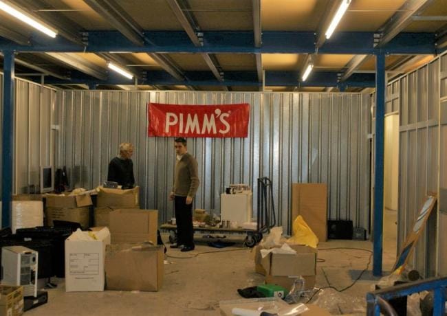 Charles, with a hint of scepticism, embarking on his journey in a 1200 sqft warehouse, accompanied by his Dad who may have questioned his decision to forgo university. The presence of a prominent Pimm's banner adds an interesting twist to the story.